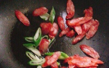 Add vegetable oil to the pan, add sausage and green onion slices and stir fry