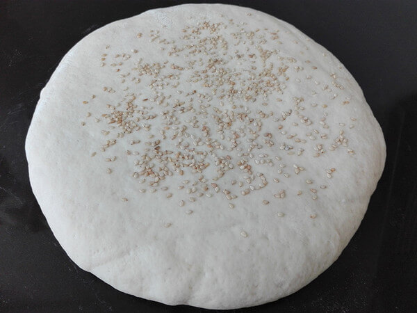 Gently roll out and roll the noodles, and spread some white sesame on the surface