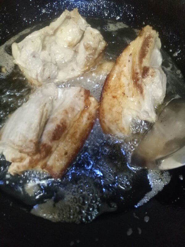 Put the pork belly skin down into the oil pan and fry until golden brown,