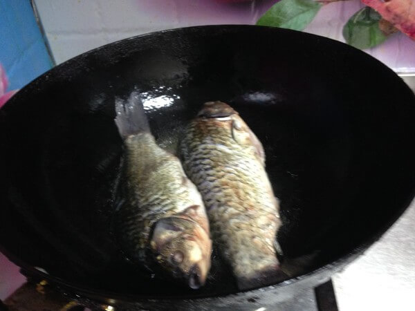 Heat a little oil in the pot, put the carp on low heat and fry until golden on both sides